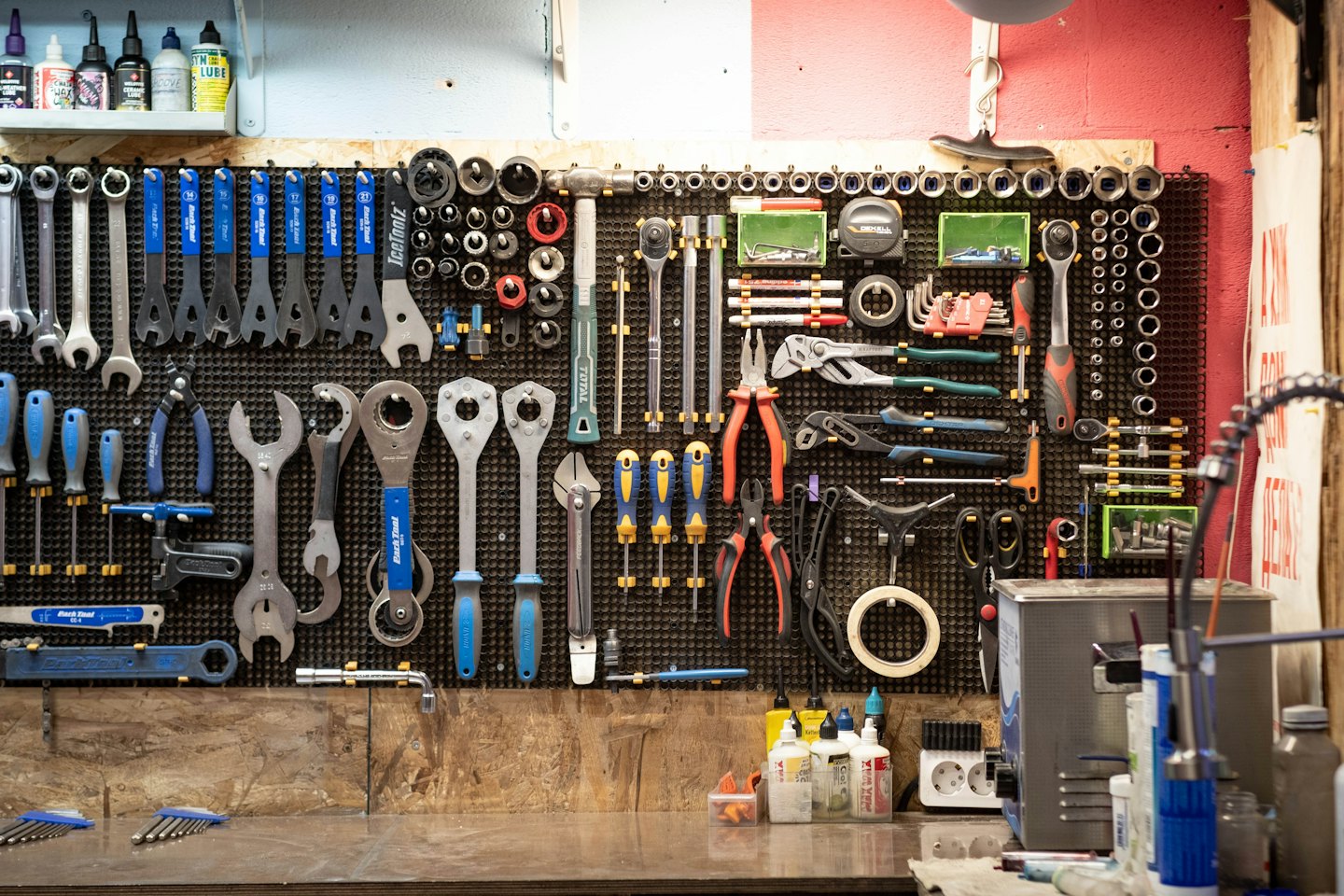 Pegboard displaying bike repair tools above a workbench with supplies.